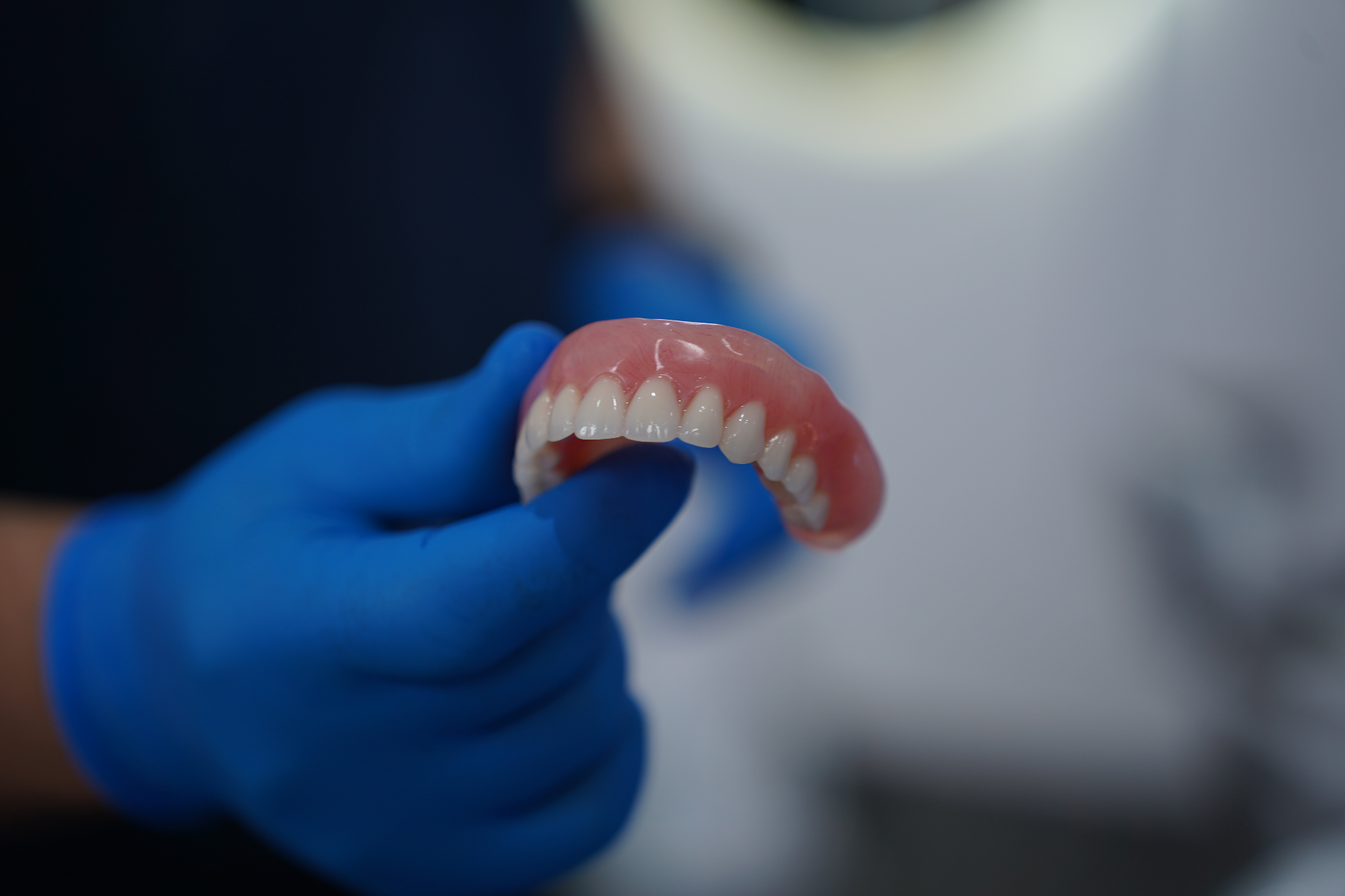 Implant-retained denture handled by clinician at Re-Ignite Dental
